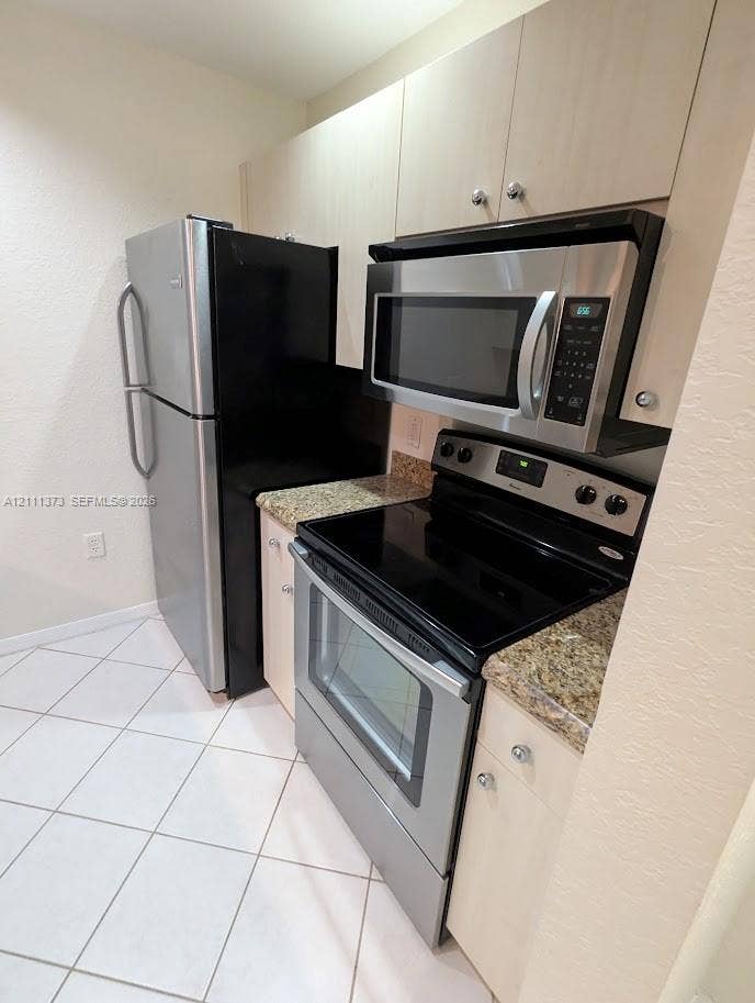 1801 N Flagler Drive, #912, West Palm Beach, West Palm Beach, FL 33401 Kitchen featuring light-finish cabinetry, stone-style countertops, stainless steel appliances, and ceramic tile flooring