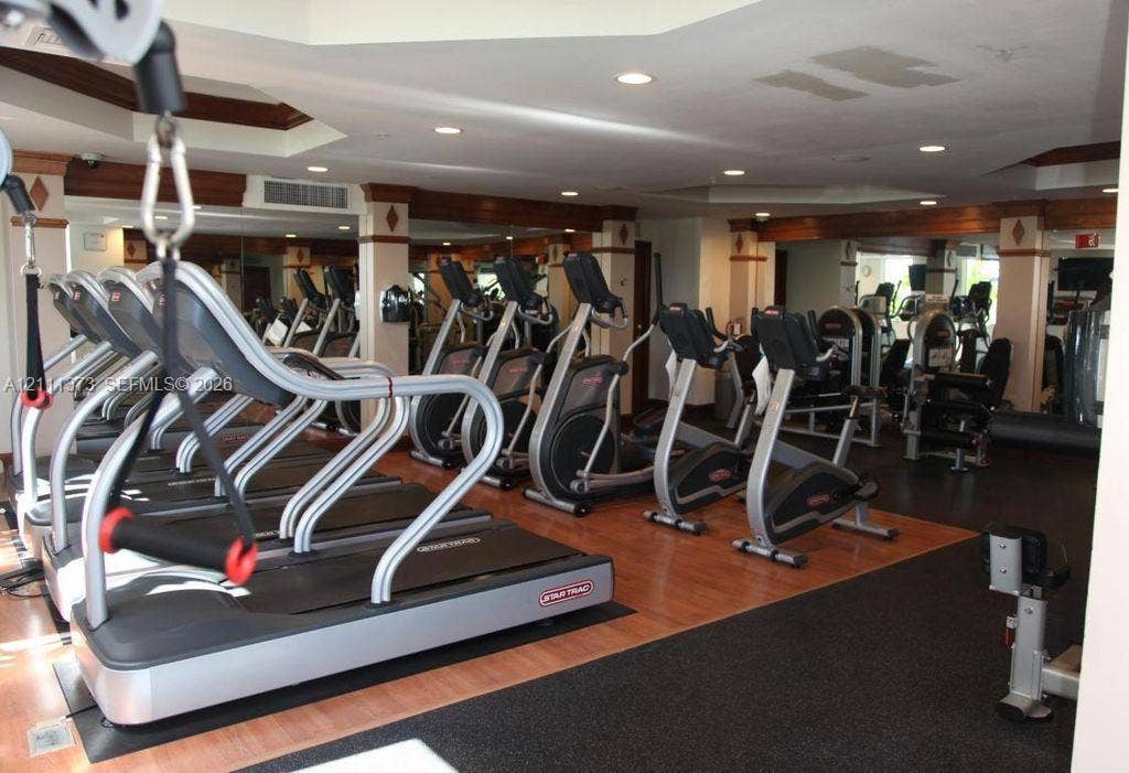 1801 N Flagler Drive, #912, West Palm Beach, West Palm Beach, FL 33401 Fitness room featuring mirrored walls, recessed ceiling lighting, wood-finish flooring, and crown molding accents on structural columns