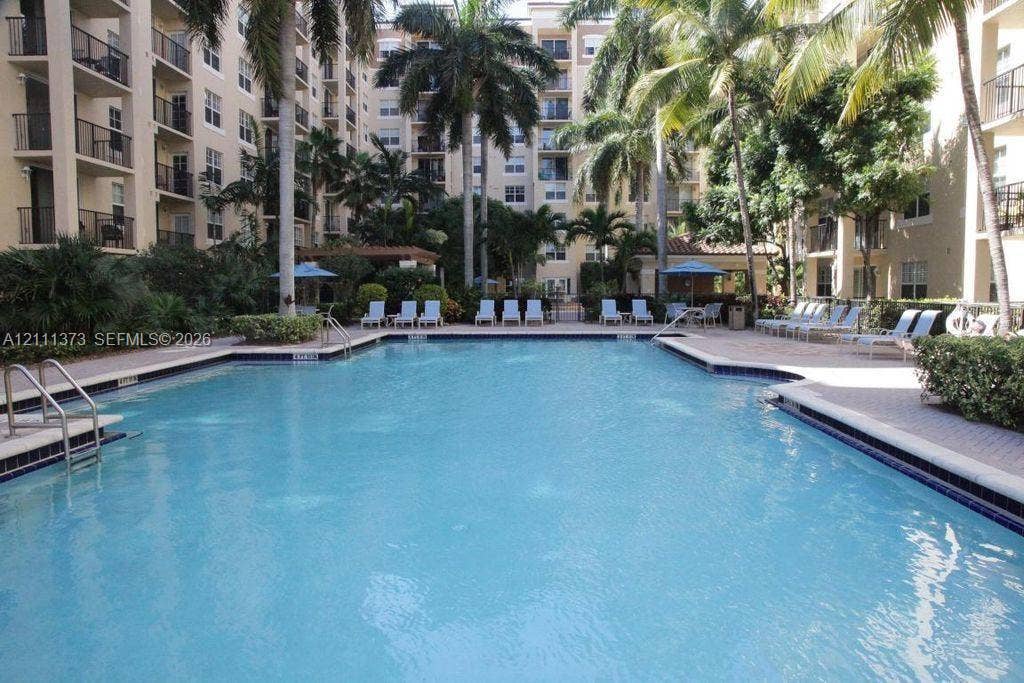 1801 N Flagler Drive, #912, West Palm Beach, West Palm Beach, FL 33401 In-ground pool with paved surround, mature palm trees, and multi-story building exterior
