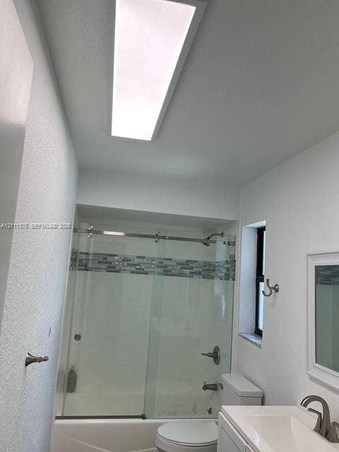 Bathroom featuring a glass-enclosed shower with decorative tile inlay, rectangular vanity with a brushed metal faucet, rectangular ceiling light fixture, and a single window