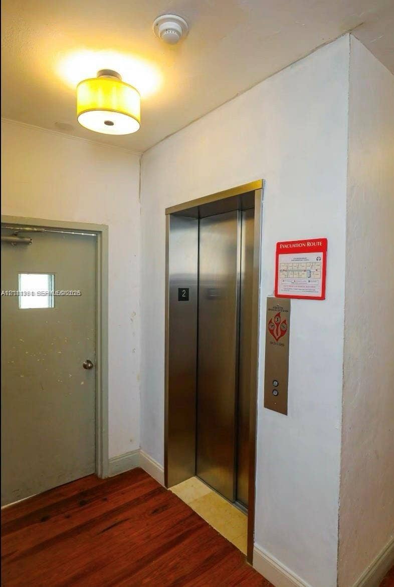 3710 Collins Avenue, #N-206, Miami Beach, FL 33140 Elevator access with stainless steel doors, drum-style ceiling light fixture, and wood-finish flooring