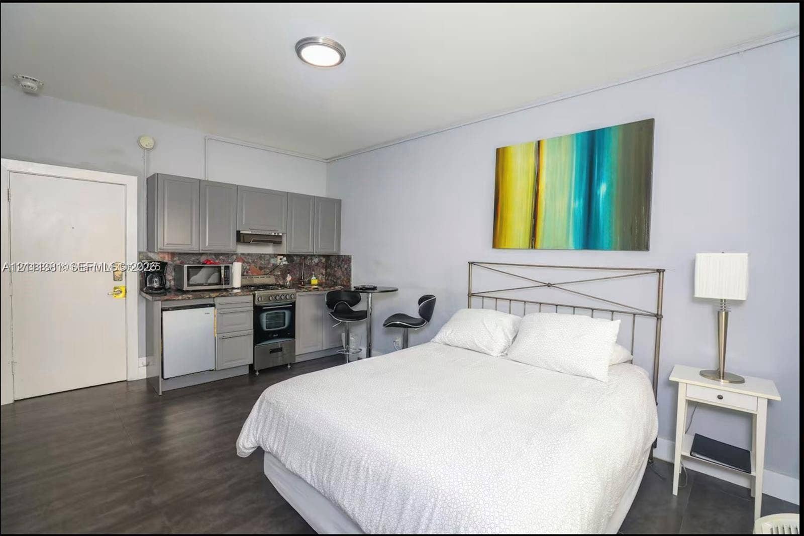 3710 Collins Avenue, #N-206, Miami Beach, FL 33140 Kitchenette featuring grey cabinetry, dark stone-finish countertops, stainless steel appliances, and wood-finish flooring