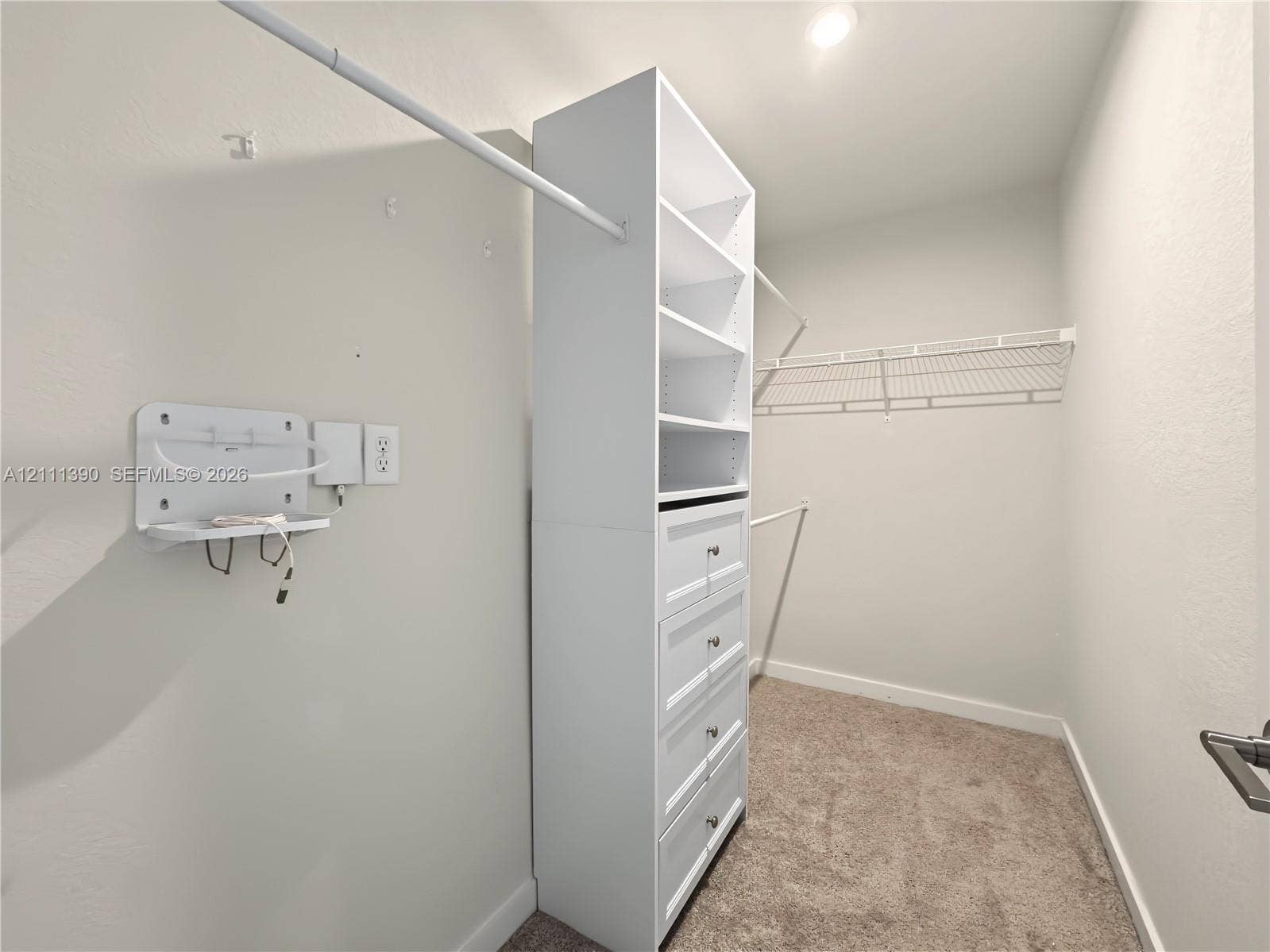 1074 NW 6th Terrace, Florida City, Florida City, FL 33034 Walk-in closet featuring white custom built-in shelving, a five-drawer dresser unit, wall-mounted wire shelving, and neutral carpeting