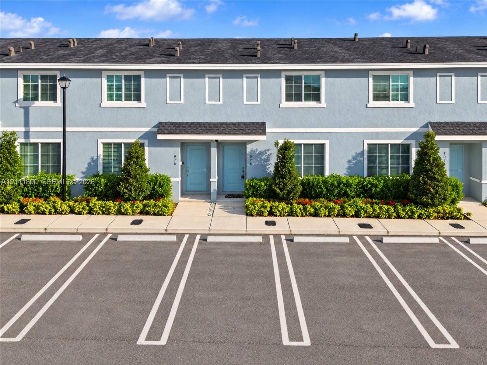1074 NW 6th Terrace, Florida City, Florida City, FL 33034 Multi-level exterior featuring light blue siding, dual-tone exterior doors, shingle roofing, and dedicated concrete parking spaces