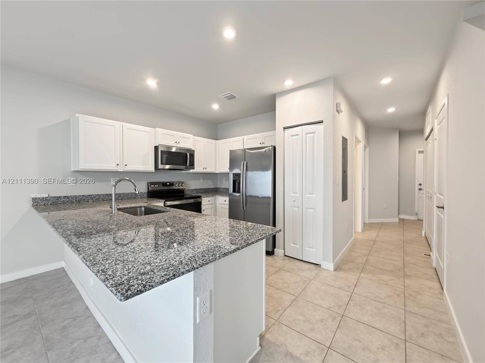1074 NW 6th Terrace, Florida City, Florida City, FL 33034 Kitchen featuring a stone countertop peninsula, white shaker-style cabinetry, stainless steel appliances, and tile flooring