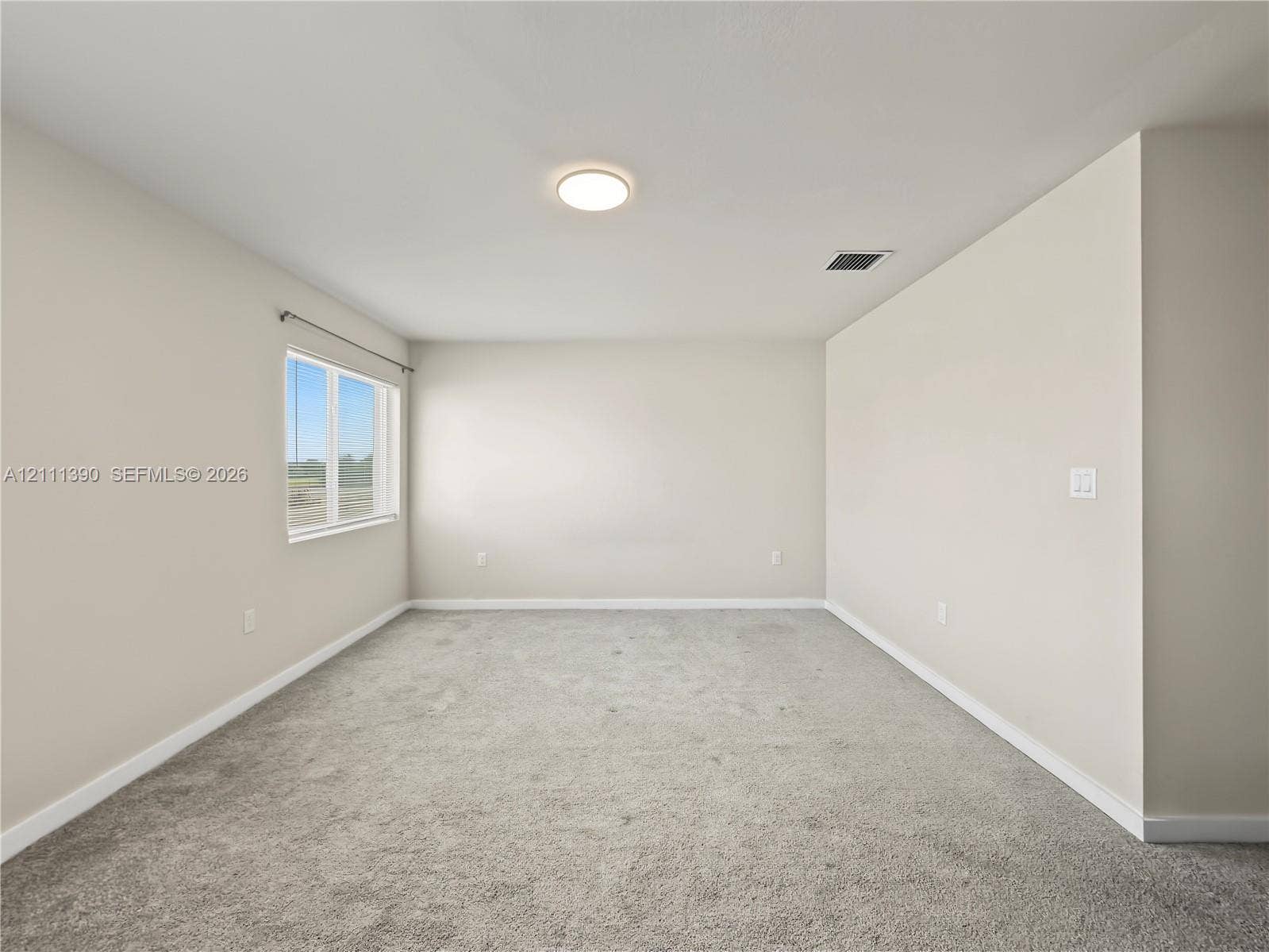 1074 NW 6th Terrace, Florida City, Florida City, FL 33034 Neutral-toned interior space featuring light-colored wall paint, plush carpeting, and a single-pane window