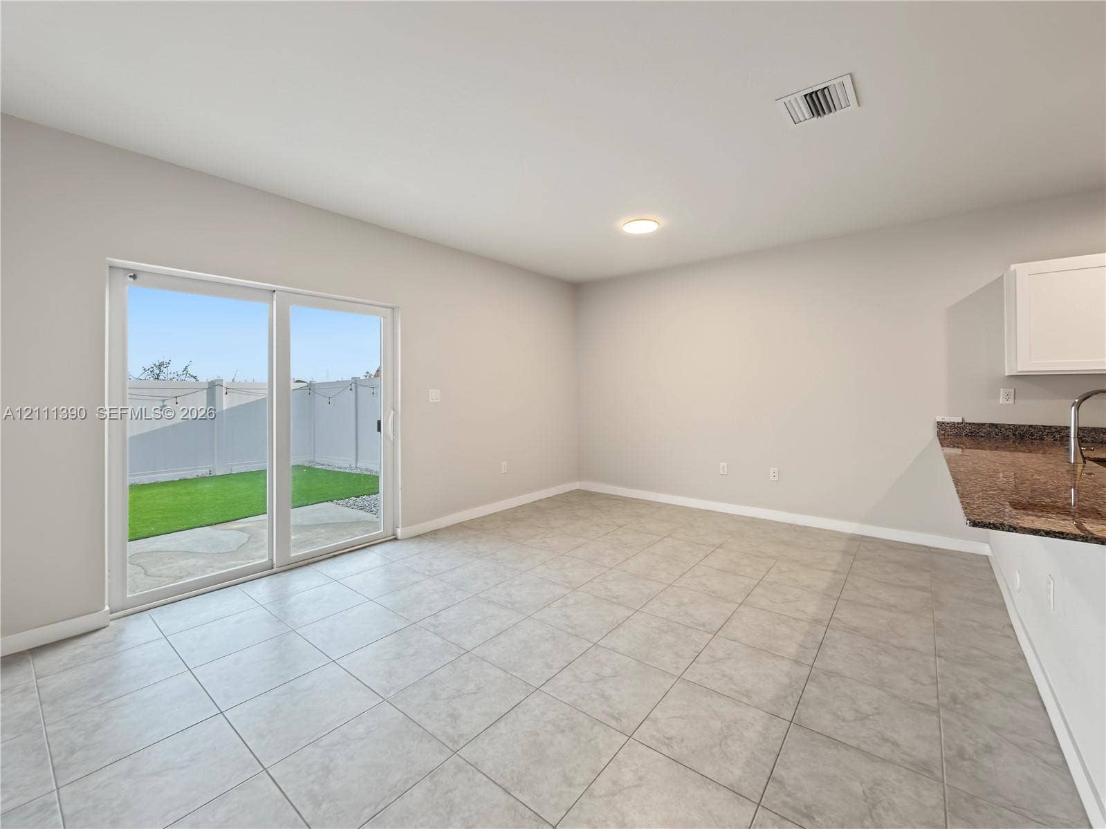 1074 NW 6th Terrace, Florida City, Florida City, FL 33034 Neutral-toned tile flooring, sliding glass door, stone-surface breakfast bar, and white cabinetry