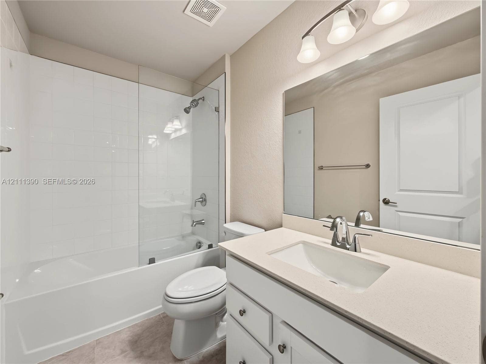 1074 NW 6th Terrace, Florida City, Florida City, FL 33034 Bathroom featuring a white vanity cabinet with a quartz countertop, an integrated rectangular sink, a large wall-mounted mirror, and a shower-tub combination with a glass panel enclosure