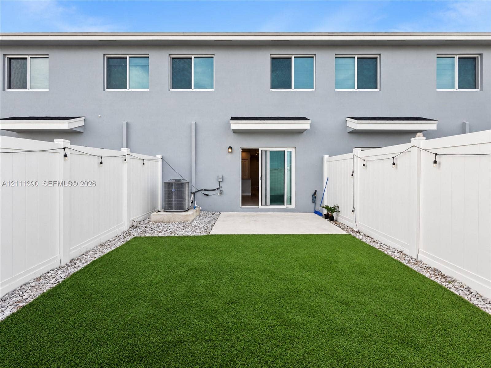 1074 NW 6th Terrace, Florida City, Florida City, FL 33034 Private backyard featuring synthetic turf, concrete patio, white vinyl privacy fencing, and exterior sliding glass door