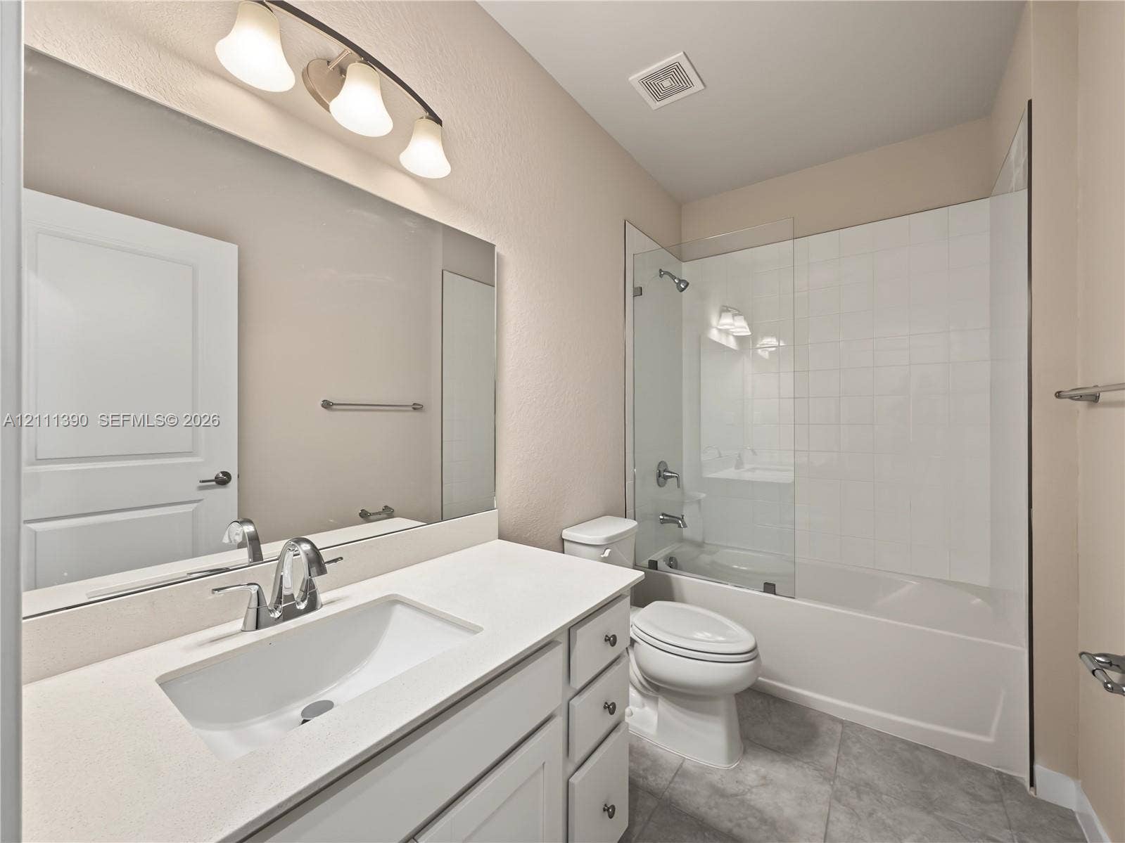 1074 NW 6th Terrace, Florida City, Florida City, FL 33034 Bathroom featuring a vanity with a white countertop and rectangular undermount sink, expansive wall-to-wall mirror, glass shower door, and tile-surround tub