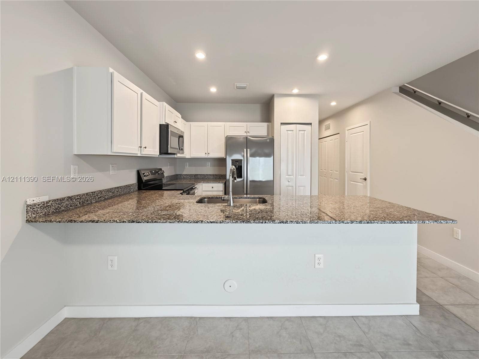 1074 NW 6th Terrace, Florida City, Florida City, FL 33034 Kitchen featuring white shaker-style cabinetry, stone-finish countertops, stainless steel appliances, a peninsula with an undermount sink, and tile flooring