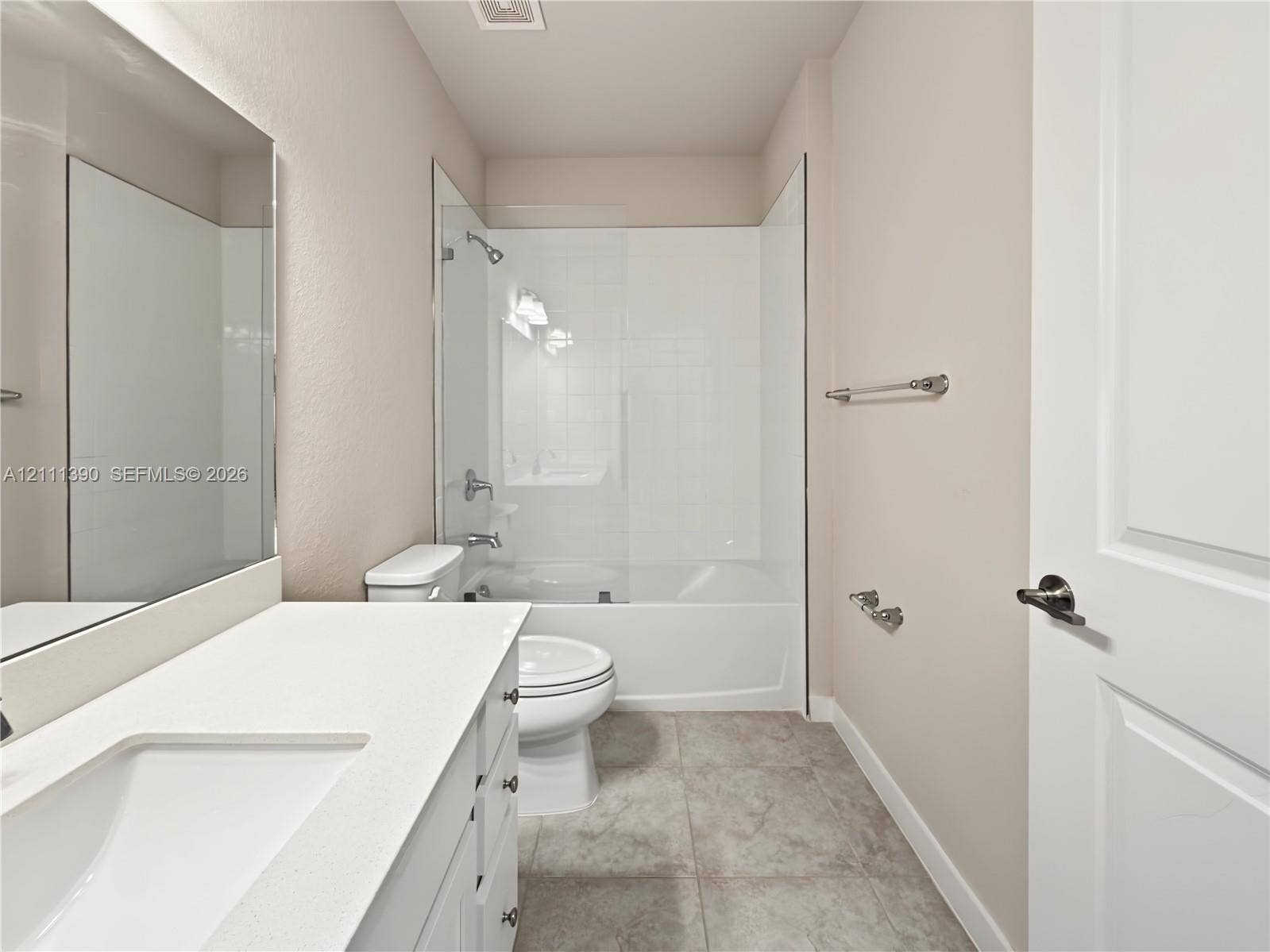1074 NW 6th Terrace, Florida City, Florida City, FL 33034 Bathroom featuring a vanity with a white countertop and rectangular undermount sink, a large wall-mounted mirror, tile flooring, and a tub-shower combination with a glass panel