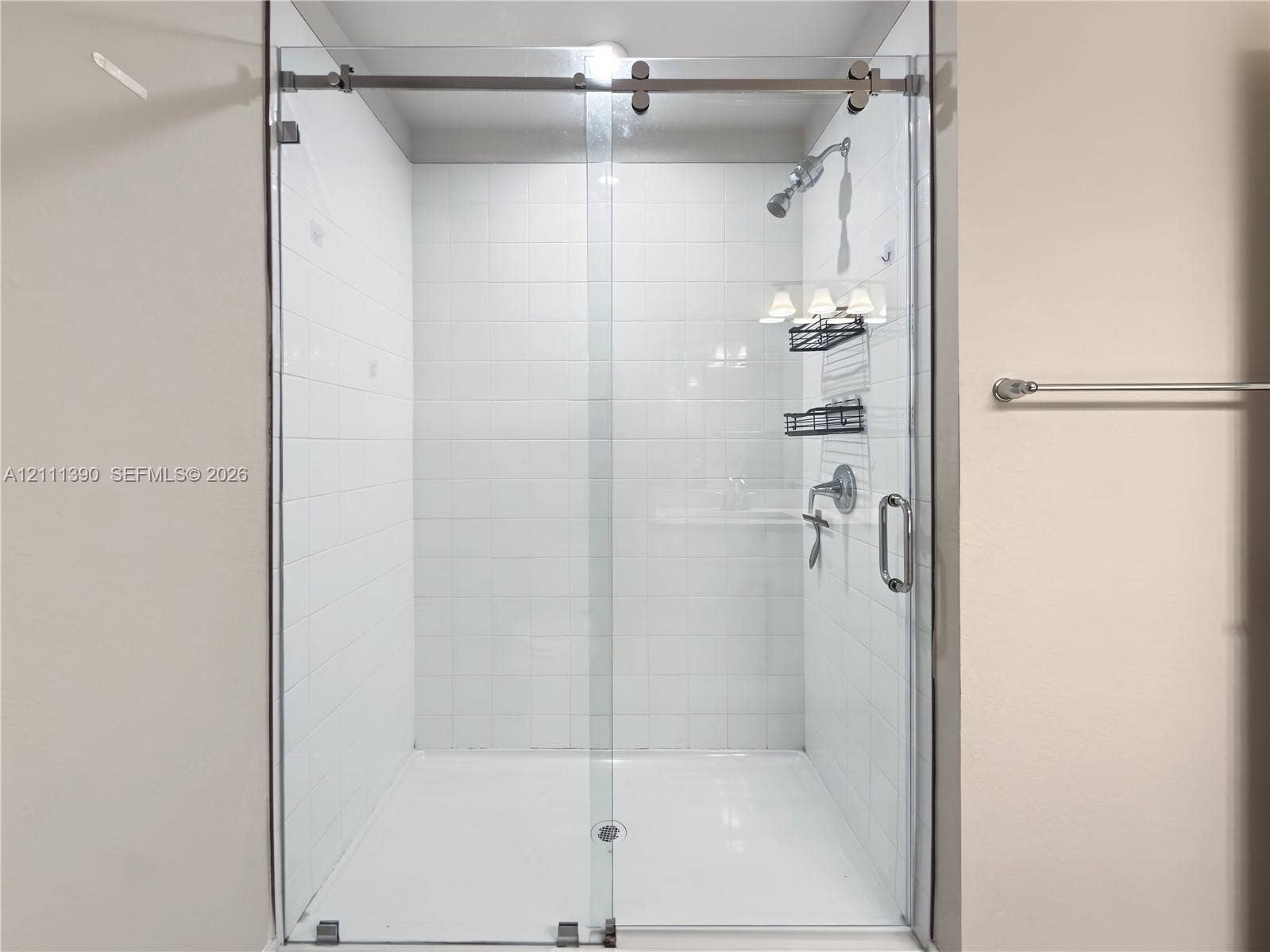 1074 NW 6th Terrace, Florida City, Florida City, FL 33034 Walk-in shower featuring white subway wall tile, a frameless glass sliding door with brushed metal hardware, and a fixed shower head