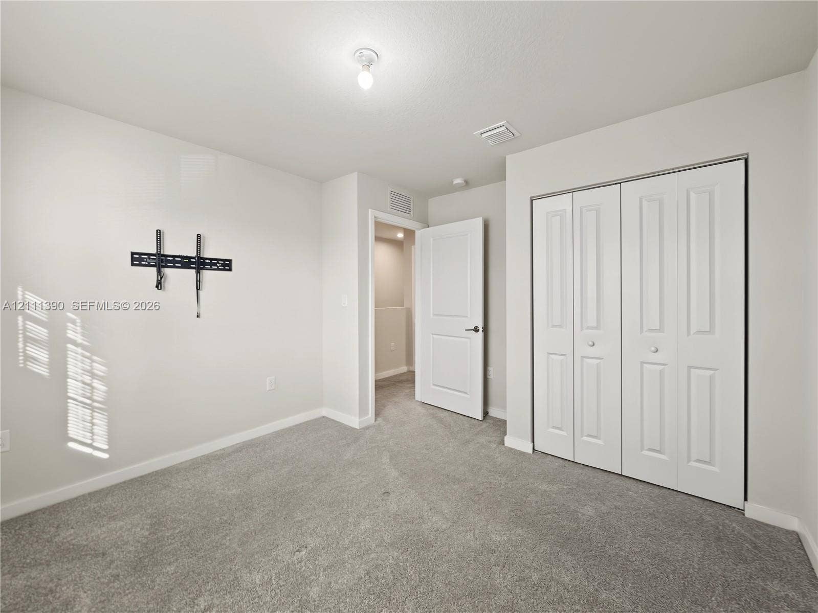 1074 NW 6th Terrace, Florida City, Florida City, FL 33034 Room featuring neutral-toned carpeting, white walls, two-panel interior door, and white bi-fold closet doors
