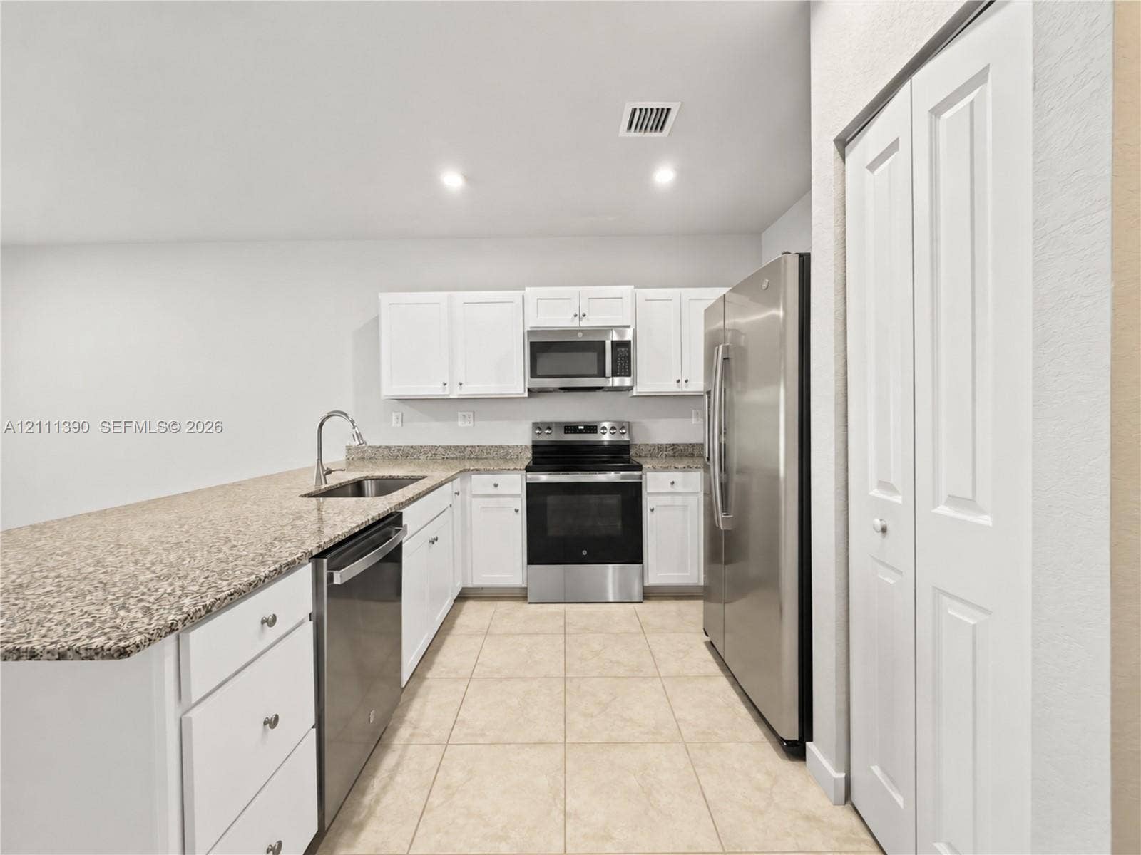 1074 NW 6th Terrace, Florida City, Florida City, FL 33034 Kitchen featuring white shaker-style cabinetry, stone-finish countertops, stainless steel appliances, ceramic tile flooring, and a double-door pantry