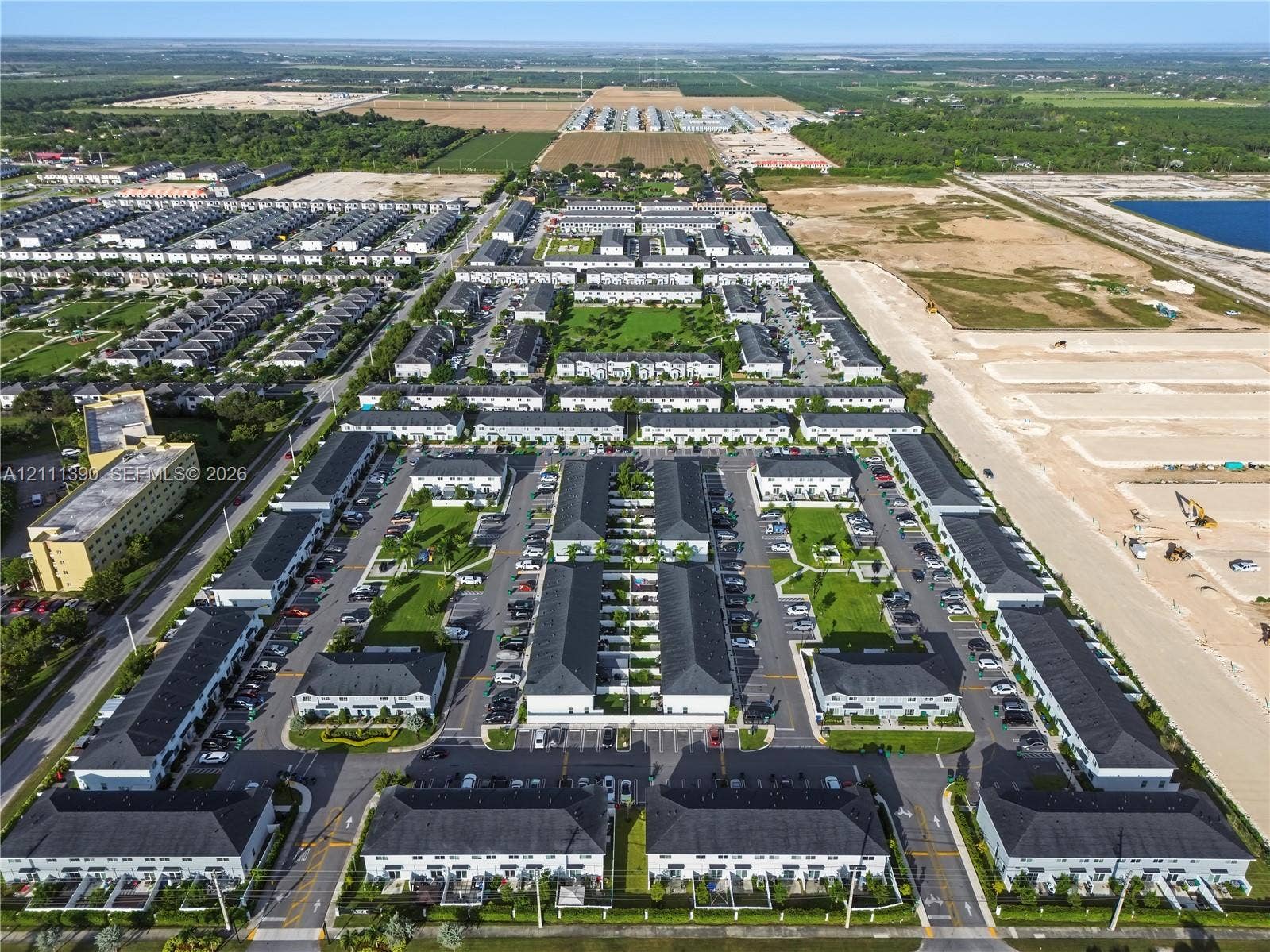 1074 NW 6th Terrace, Florida City, Florida City, FL 33034 Aerial perspective of a multi-unit residential community featuring uniform architectural design, pitched roofs, paved internal roadways, and landscaped common green spaces