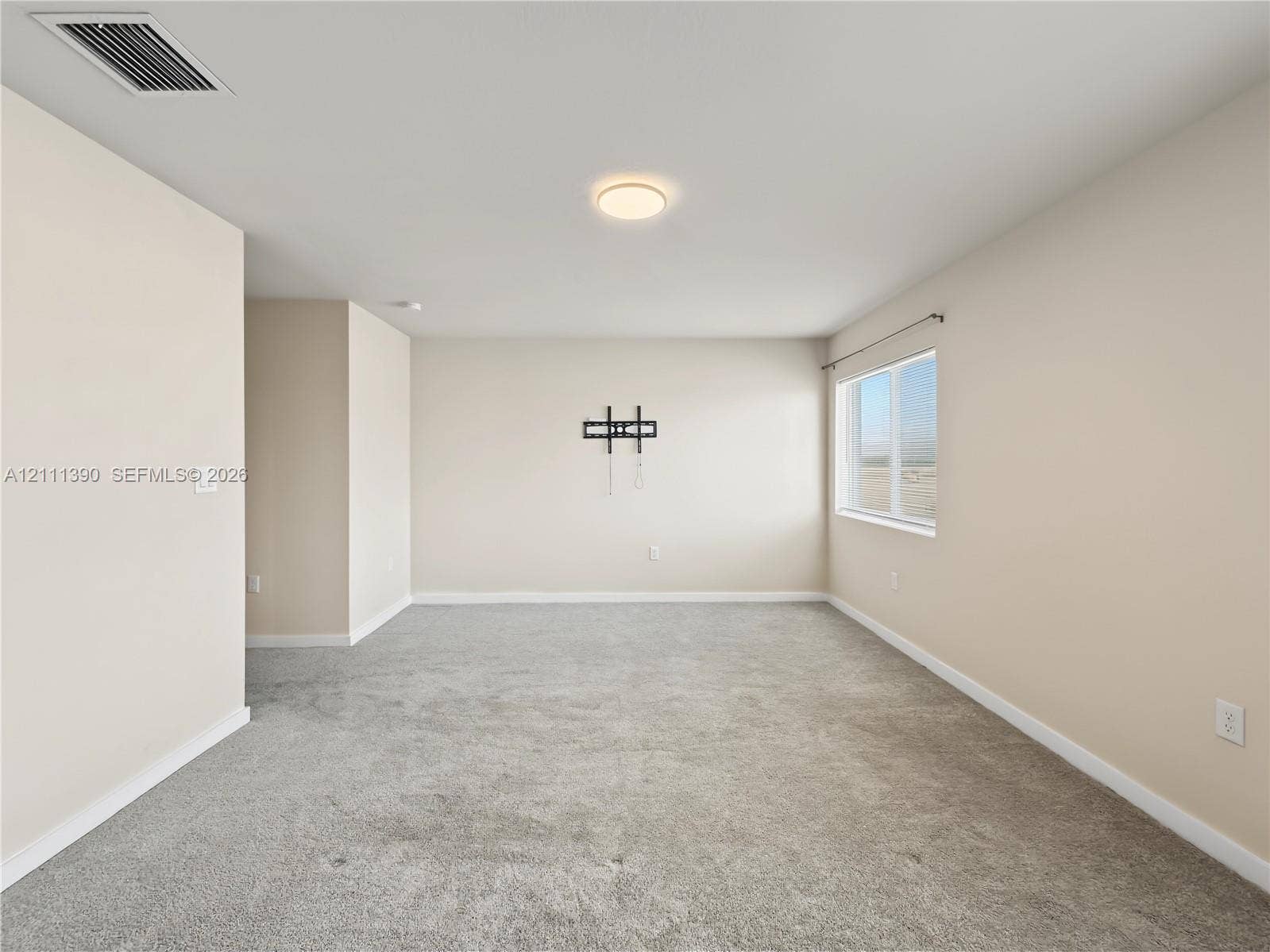 1074 NW 6th Terrace, Florida City, Florida City, FL 33034 Neutral-toned interior space featuring neutral wall-to-wall carpeting, a single-pane window, and a flush-mount ceiling light fixture