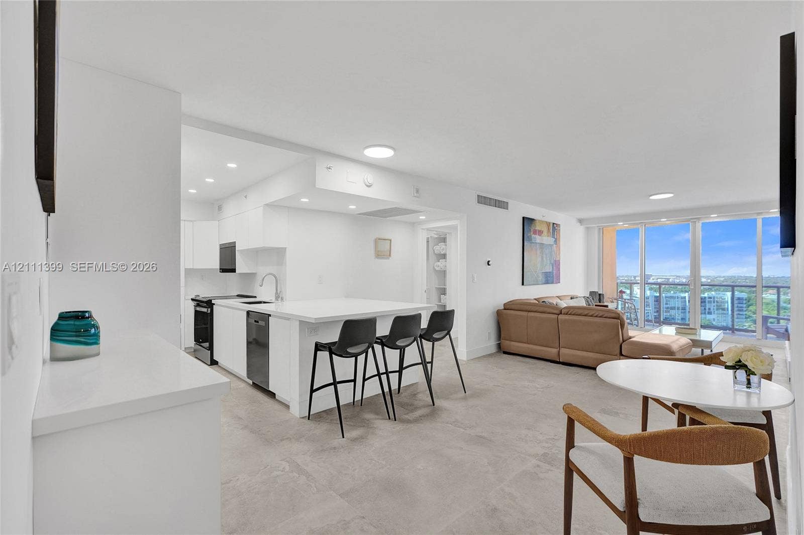 2501 S Ocean Drive, #1630, Hollywood, Hollywood, FL 33019 Open-concept kitchen featuring white cabinetry, a stone-finish island with integrated breakfast bar, recessed lighting, and large-format tile flooring, complete with floor-to-ceiling windows