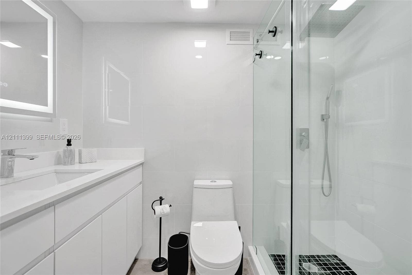 2501 S Ocean Drive, #1630, Hollywood, Hollywood, FL 33019 Bathroom featuring a glass-enclosed walk-in shower with a rainfall showerhead, white vanity with integrated basin, polished metal hardware, and LED-backlit mirror