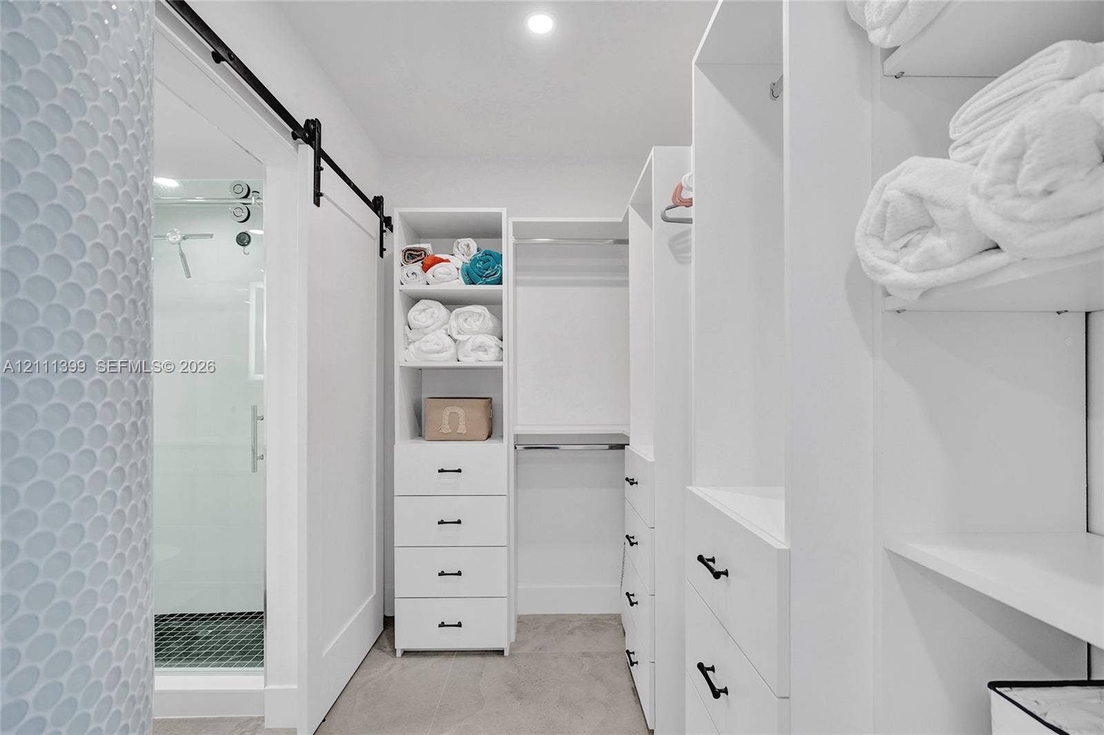 2501 S Ocean Drive, #1630, Hollywood, Hollywood, FL 33019 Walk-in closet featuring white built-in cabinetry, custom shelving, multiple drawers with matte black hardware, and a sliding barn-style door
