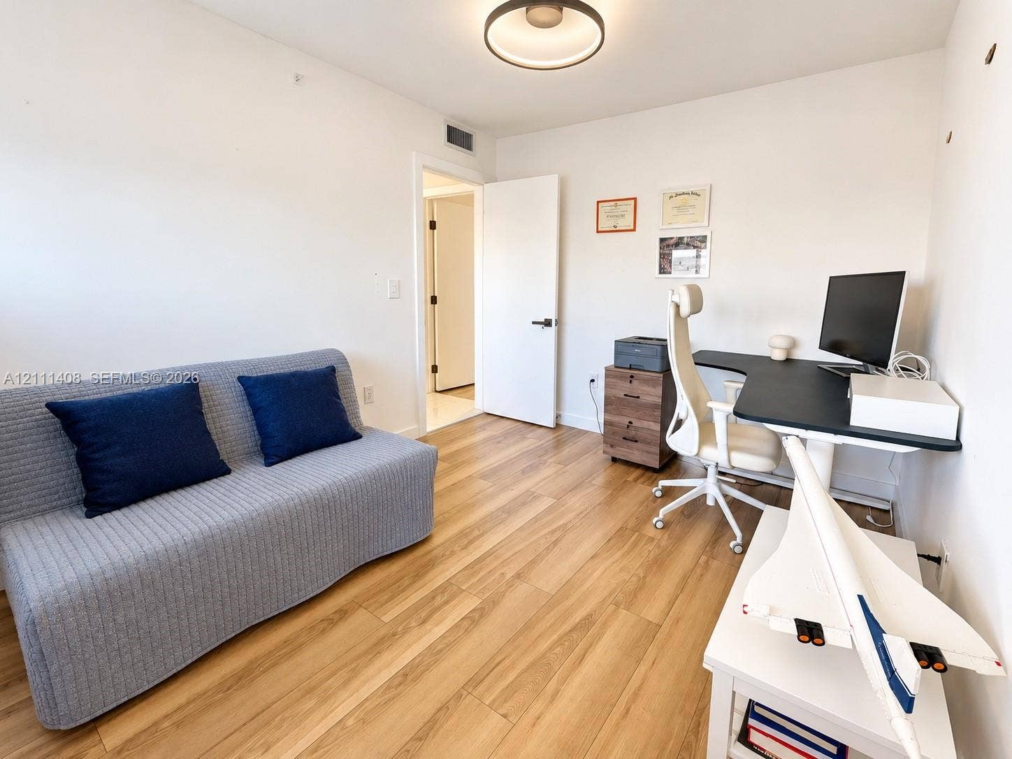 1700 N River Drive, #1004, Miami, FL 33125 Room featuring wood-finish flooring, a horizontal sliding window with roller shade, and a bi-fold closet door