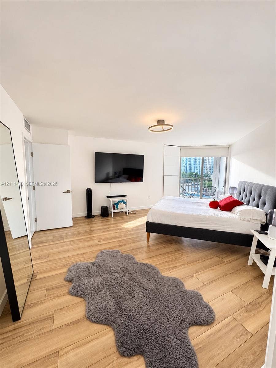 1700 N River Drive, #1004, Miami, FL 33125 Wood-finish flooring, floor-to-ceiling sliding glass doors, and a modern circular LED ceiling fixture