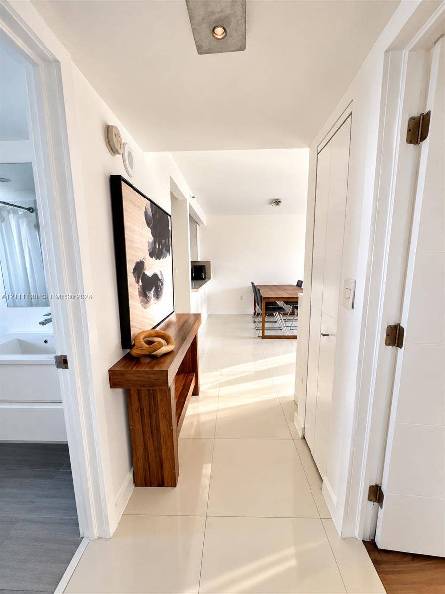 1700 N River Drive, #1004, Miami, FL 33125 Open-concept interior featuring polished tile flooring, white cabinetry, stainless steel appliances, and flush-mount ceiling lighting