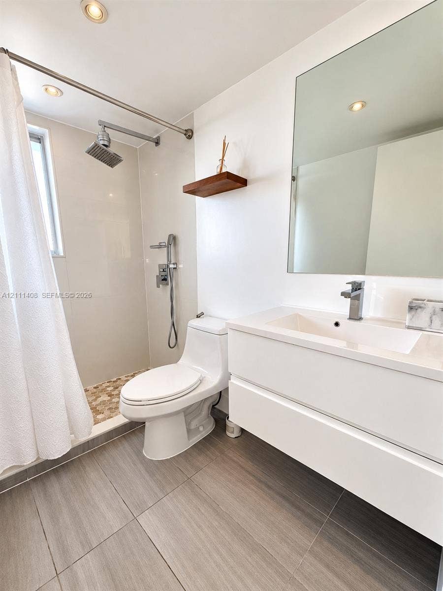 1700 N River Drive, #1004, Miami, FL 33125 Room featuring wood-finish flooring, a circular modern flush-mount light fixture, and a built-in closet with double-panel doors