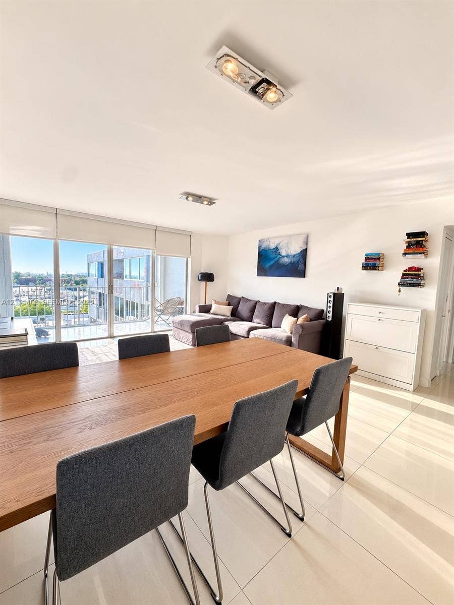 1700 N River Drive, #1004, Miami, FL 33125 Large-format tile flooring, recessed ceiling lighting, and floor-to-ceiling glass sliding doors opening to a balcony with waterfront and city scenery