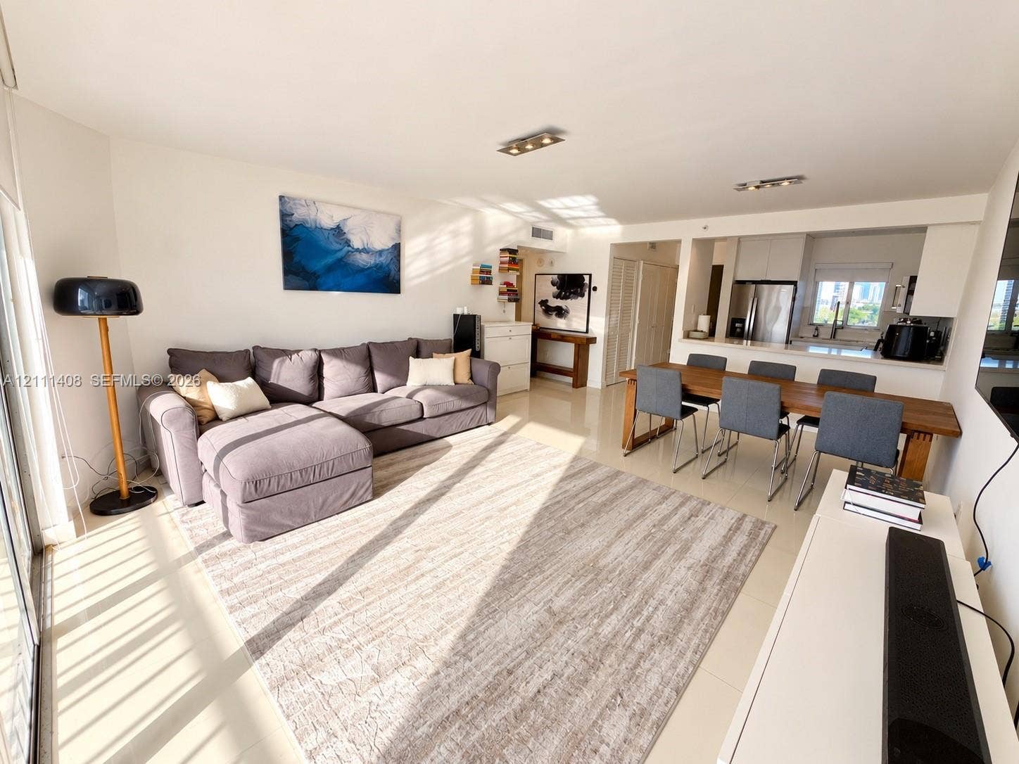 1700 N River Drive, #1004, Miami, FL 33125 Open-concept floor plan featuring neutral tile flooring, recessed track lighting, and a kitchen equipped with stainless steel appliances