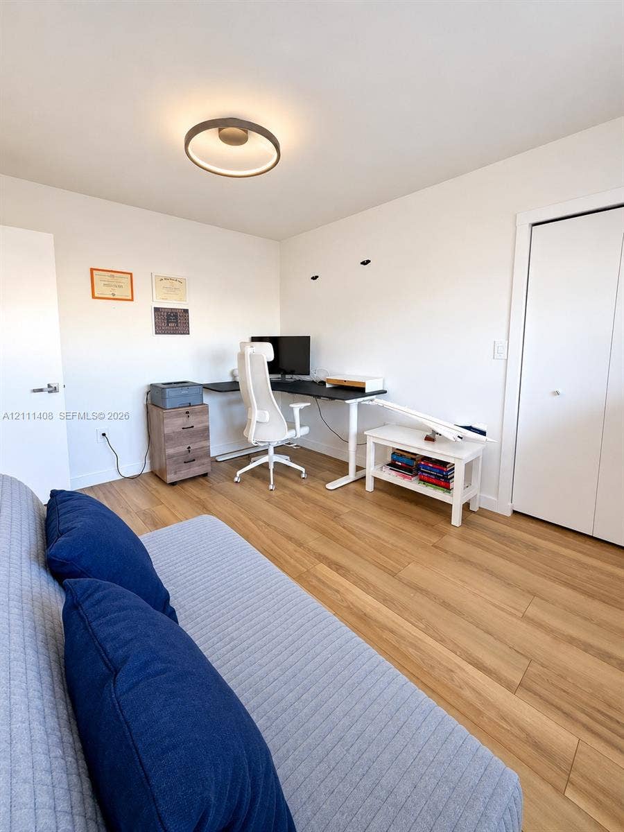 1700 N River Drive, #1004, Miami, FL 33125 Interior room featuring light-toned wood-finish flooring, a contemporary flush-mount ceiling light fixture, and a solid-core interior door with matte black hardware