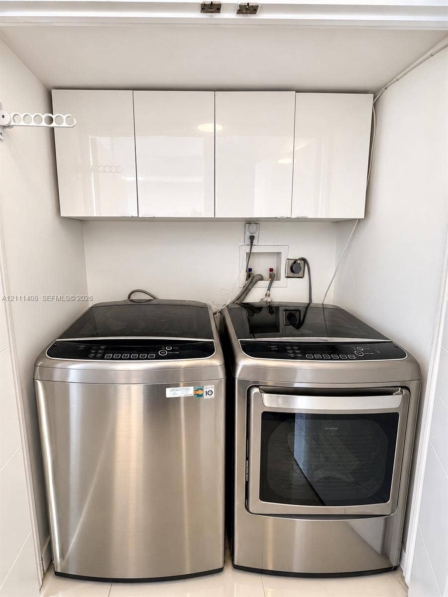 1700 N River Drive, #1004, Miami, FL 33125 Kitchen featuring flat-panel white cabinetry, solid-surface countertops with a breakfast bar, stainless steel appliances, and a single-basin undermount sink with a gooseneck faucet