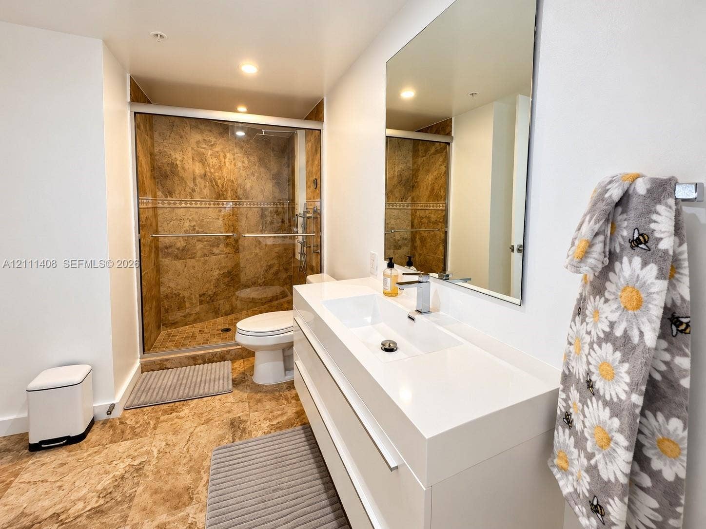 1700 N River Drive, #1004, Miami, FL 33125 Wood-finish flooring, sliding glass door with balcony access, built-in floor-to-ceiling cabinetry, minimalist geometric flush-mount lighting, and bi-fold closet doors