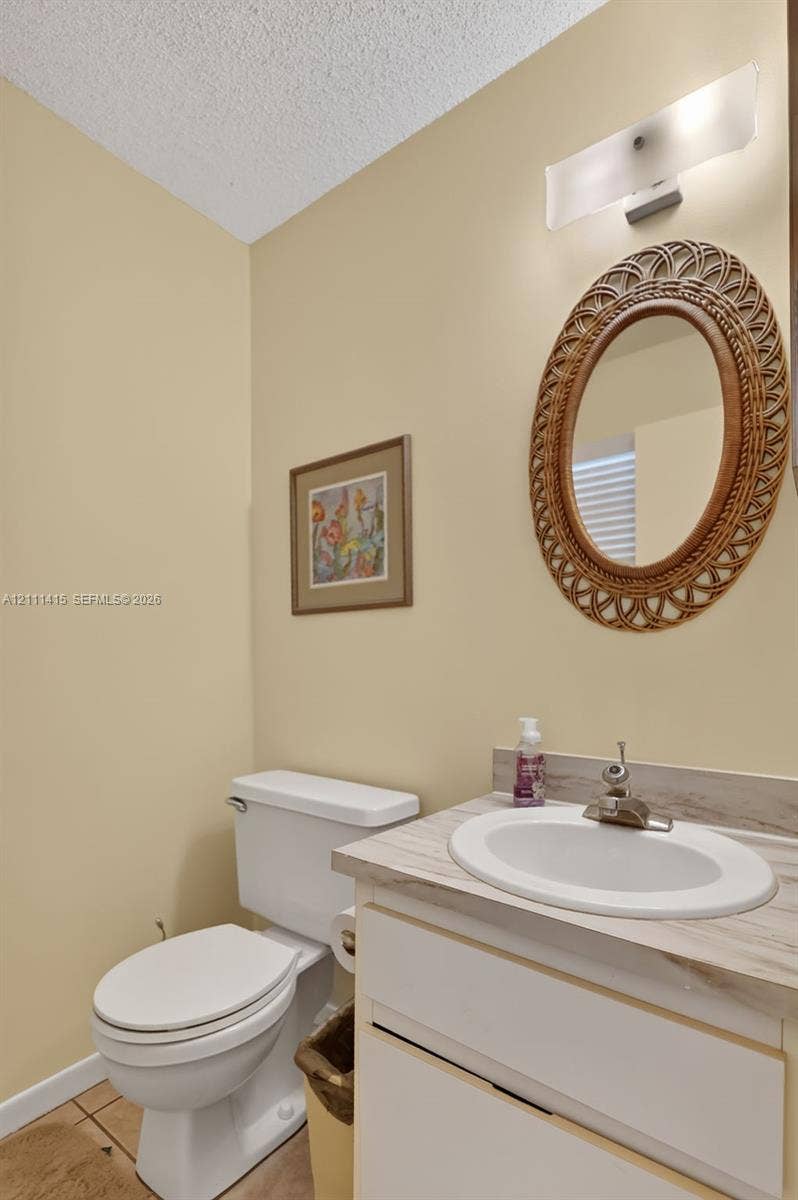 9423 S Ocean Drive, #80, Jensen Beach, FL 34957 Vanity cabinet with a neutral-toned countertop, undermount sink, chrome faucet fixture, and wall-mounted frosted glass lighting