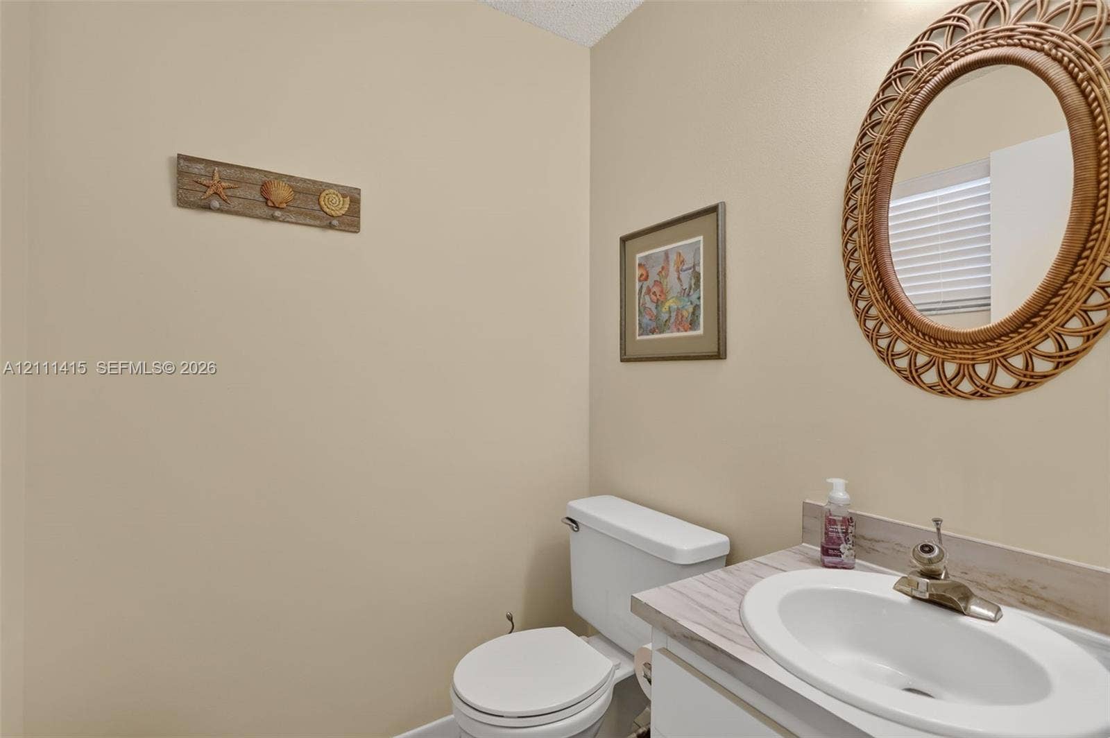 9423 S Ocean Drive, #80, Jensen Beach, FL 34957 Neutral-toned powder room featuring a vanity with a white integrated oval sink, stone-finish laminate countertop, and a classic dual-handle faucet