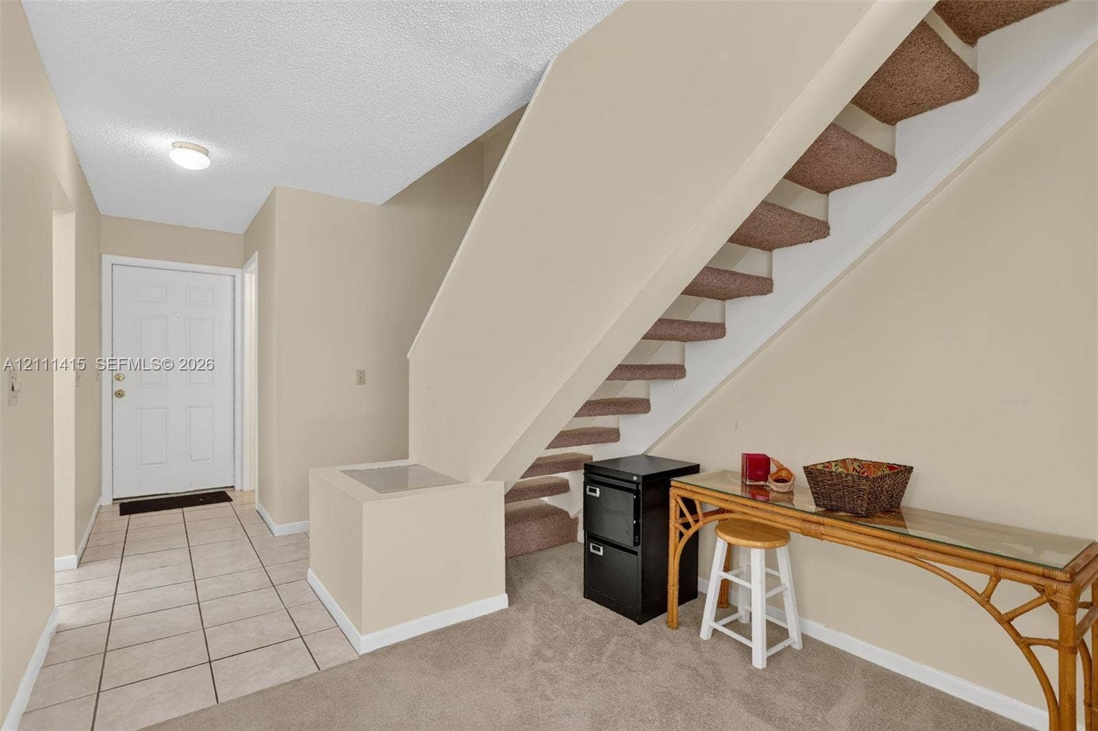 9423 S Ocean Drive, #80, Jensen Beach, FL 34957 Foyer featuring neutral-toned tile flooring, carpeted staircase with enclosed structural balustrade, and a recessed ceiling light fixture