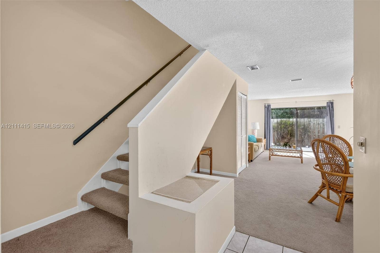 9423 S Ocean Drive, #80, Jensen Beach, FL 34957 Staircase featuring carpeted steps and a metal handrail, finished with neutral wall paint and a sliding glass door