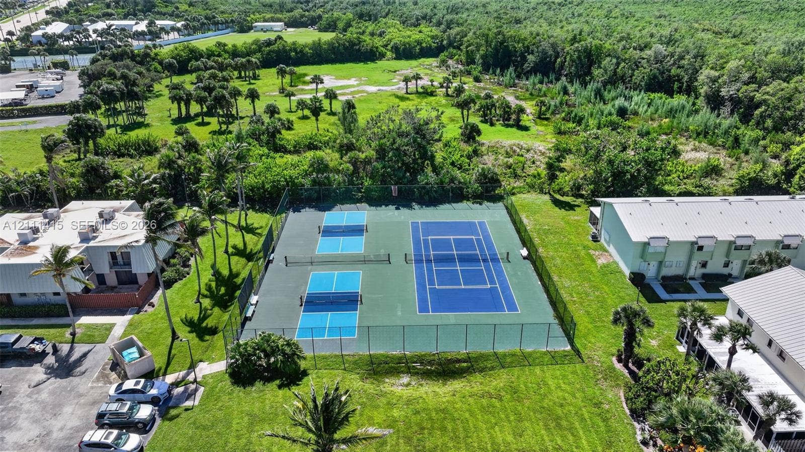 9423 S Ocean Drive, #80, Jensen Beach, FL 34957 Fenced recreation area featuring a tennis court and two pickleball courts with perimeter chain-link enclosures