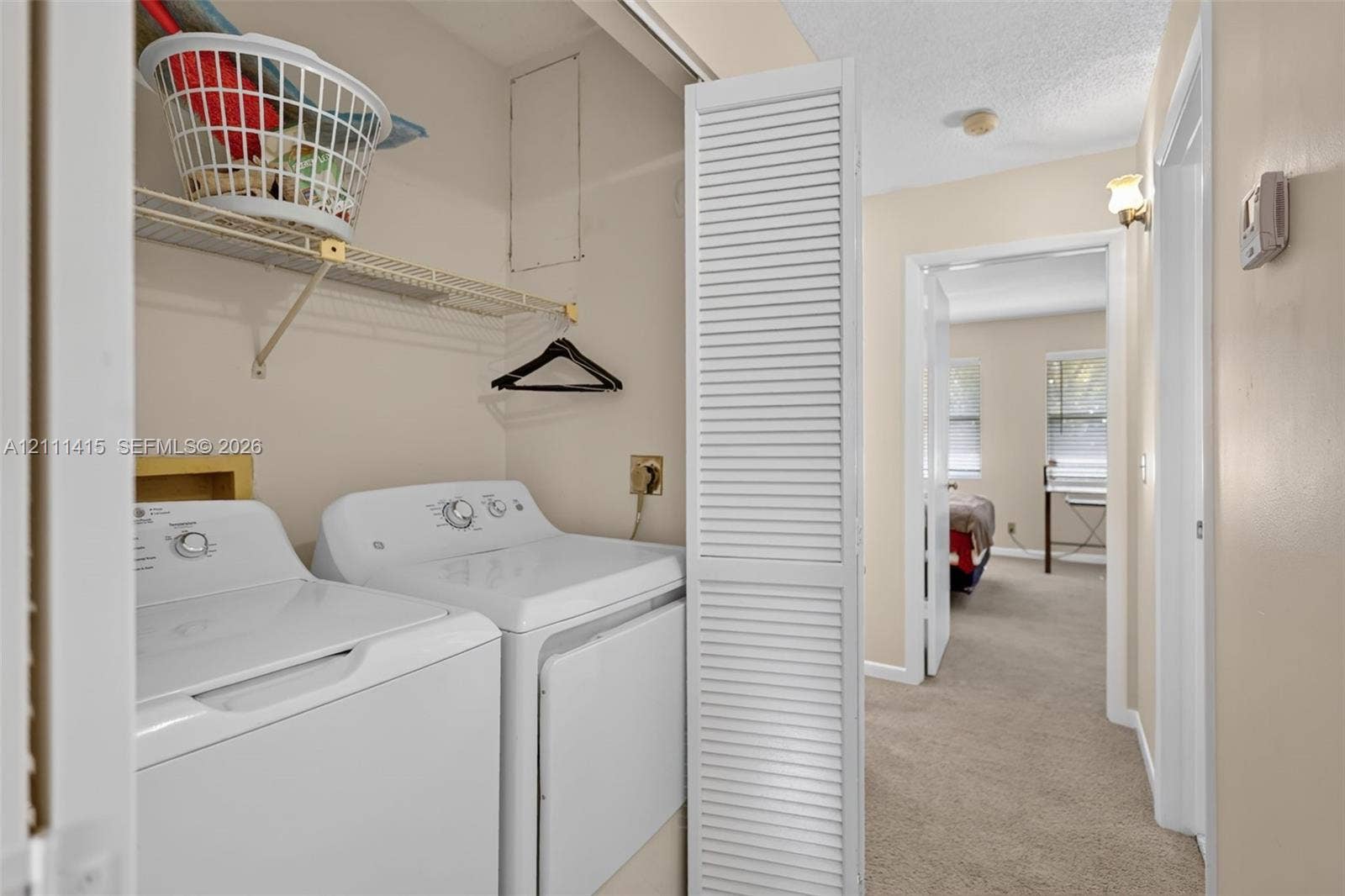 9423 S Ocean Drive, #80, Jensen Beach, FL 34957 Laundry closet featuring bi-fold louvered doors and overhead wire shelving