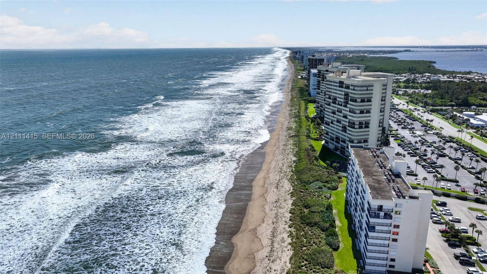9423 S Ocean Drive, #80, Jensen Beach, FL 34957 Coastal high-rise residence featuring direct ocean frontage, private balconies, expansive shoreline, and paved surface parking