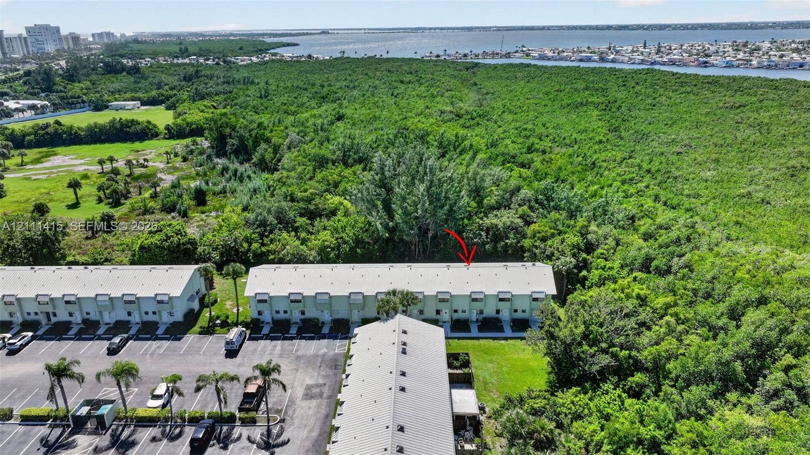 9423 S Ocean Drive, #80, Jensen Beach, FL 34957 Multi-unit residential structure featuring a light-toned exterior finish, metal roofing, paved surface parking, and exterior landscaping