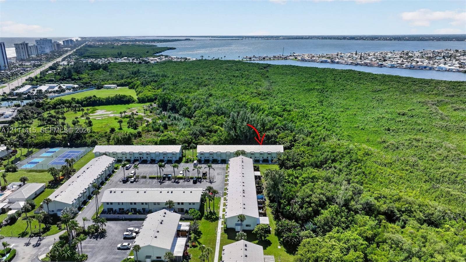 9423 S Ocean Drive, #80, Jensen Beach, FL 34957 Aerial perspective of a multi-unit complex featuring surface parking, on-site tennis courts, established landscaping, and proximity to coastal waterways