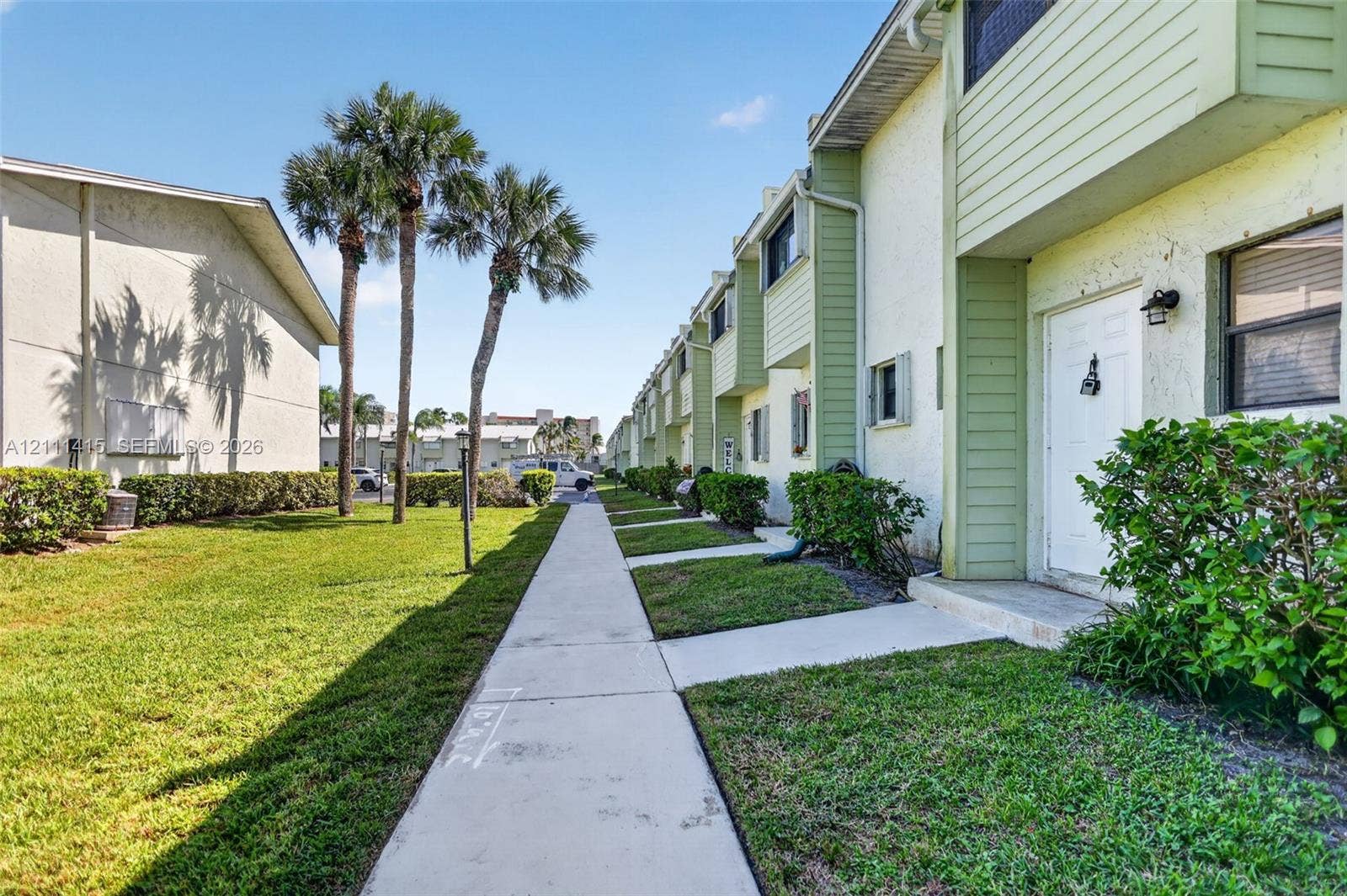 9423 S Ocean Drive, #80, Jensen Beach, FL 34957 Multi-level exterior featuring light-toned stucco and horizontal siding, concrete walkway, and palm trees