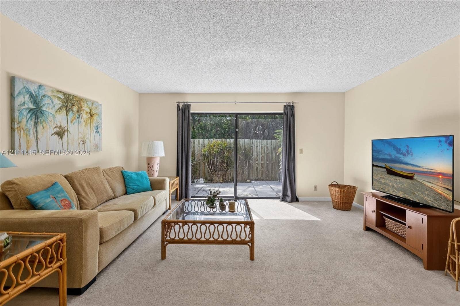 9423 S Ocean Drive, #80, Jensen Beach, FL 34957 Living space featuring wall-to-wall carpeting, textured ceiling, and sliding glass door with external patio access