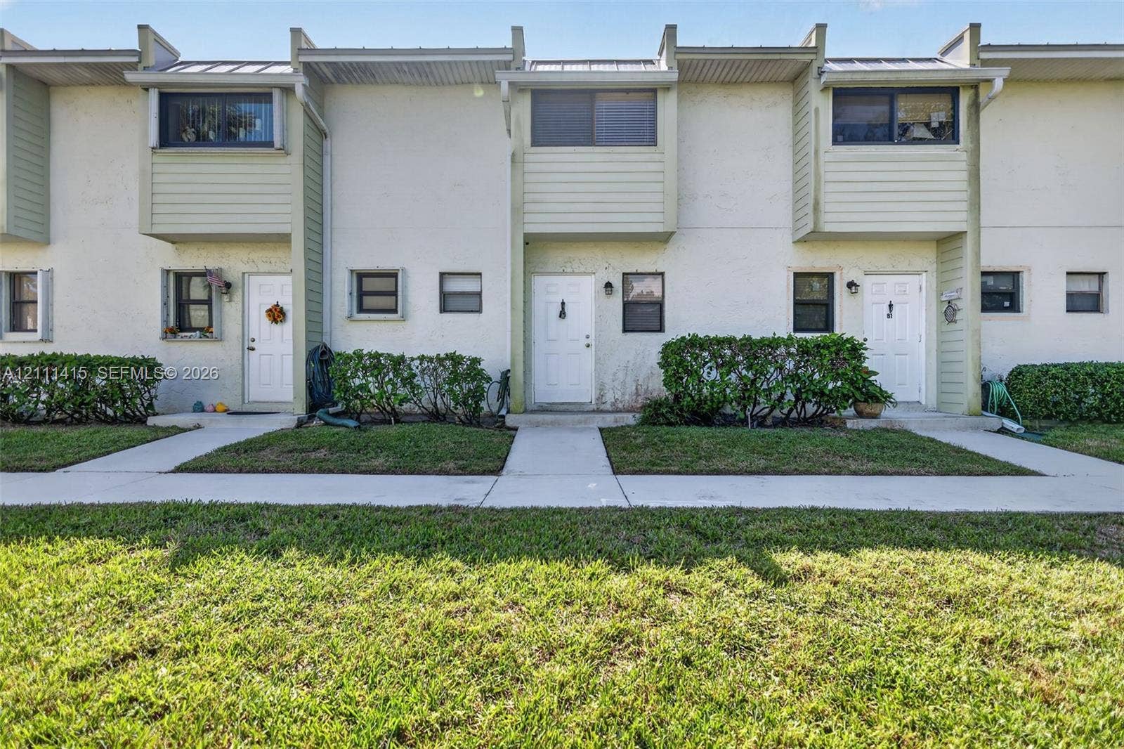 9423 S Ocean Drive, #80, Jensen Beach, FL 34957 Multi-story exterior featuring light-toned stucco, horizontal siding accents, metal roof detailing, and concrete pathways
