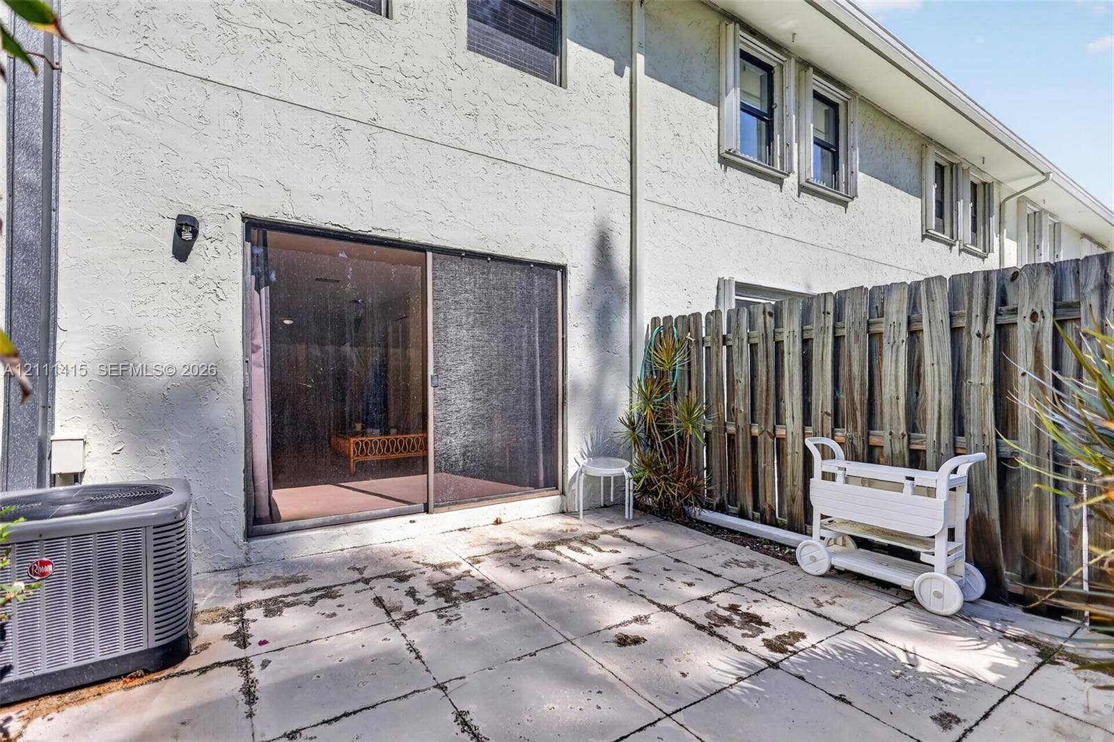 9423 S Ocean Drive, #80, Jensen Beach, FL 34957 Rear exterior featuring a concrete paver patio, sliding glass door, and a wood privacy fence