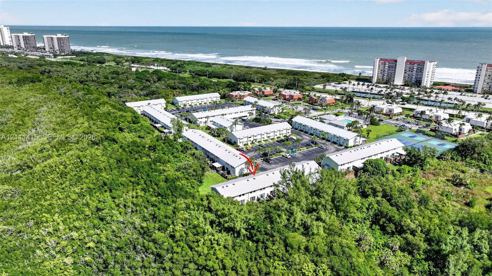 9423 S Ocean Drive, #80, Jensen Beach, FL 34957 Aerial perspective of a multi-unit residential complex featuring metal roofing and proximity to coastal shoreline and natural vegetation