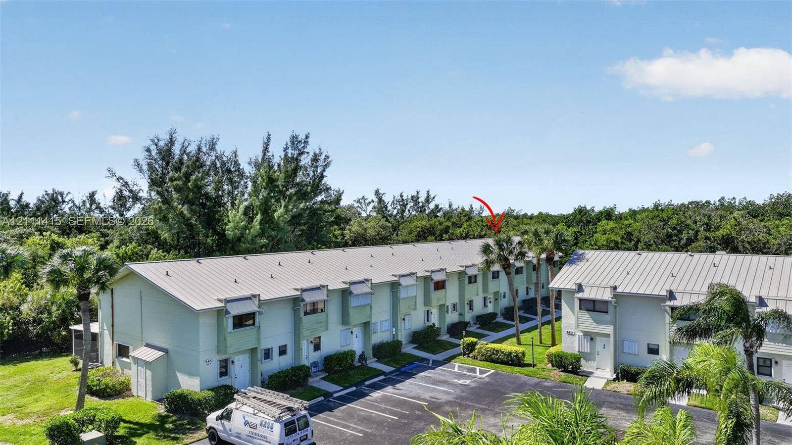 9423 S Ocean Drive, #80, Jensen Beach, FL 34957 Multi-unit building exterior featuring a metal roof, exterior window shutters, and landscaped grounds with mature palms