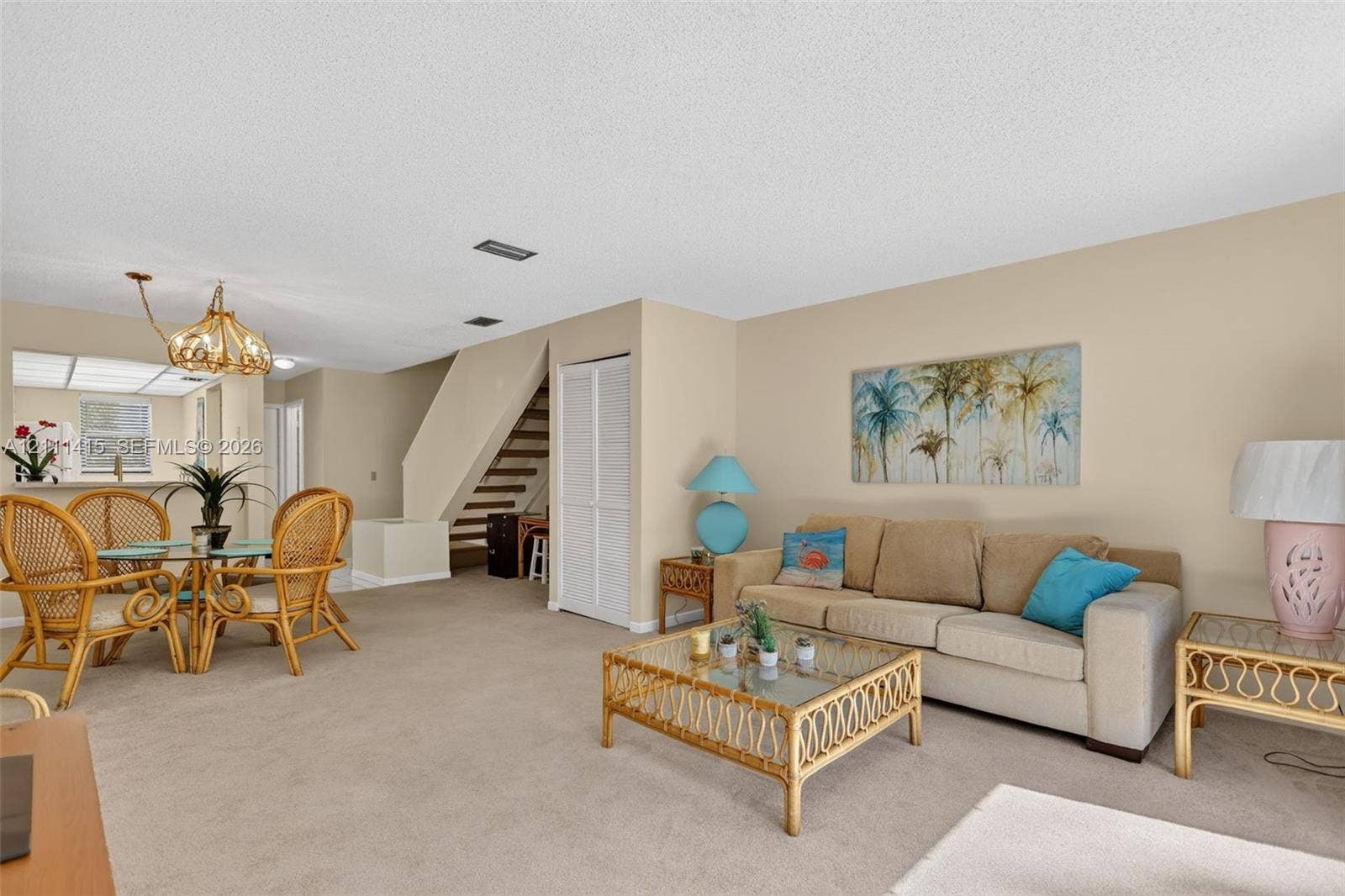 9423 S Ocean Drive, #80, Jensen Beach, FL 34957 Open-concept floor plan featuring neutral wall finishes, wall-to-wall carpeting, a multi-tiered staircase with open risers, and a decorative pendant light fixture