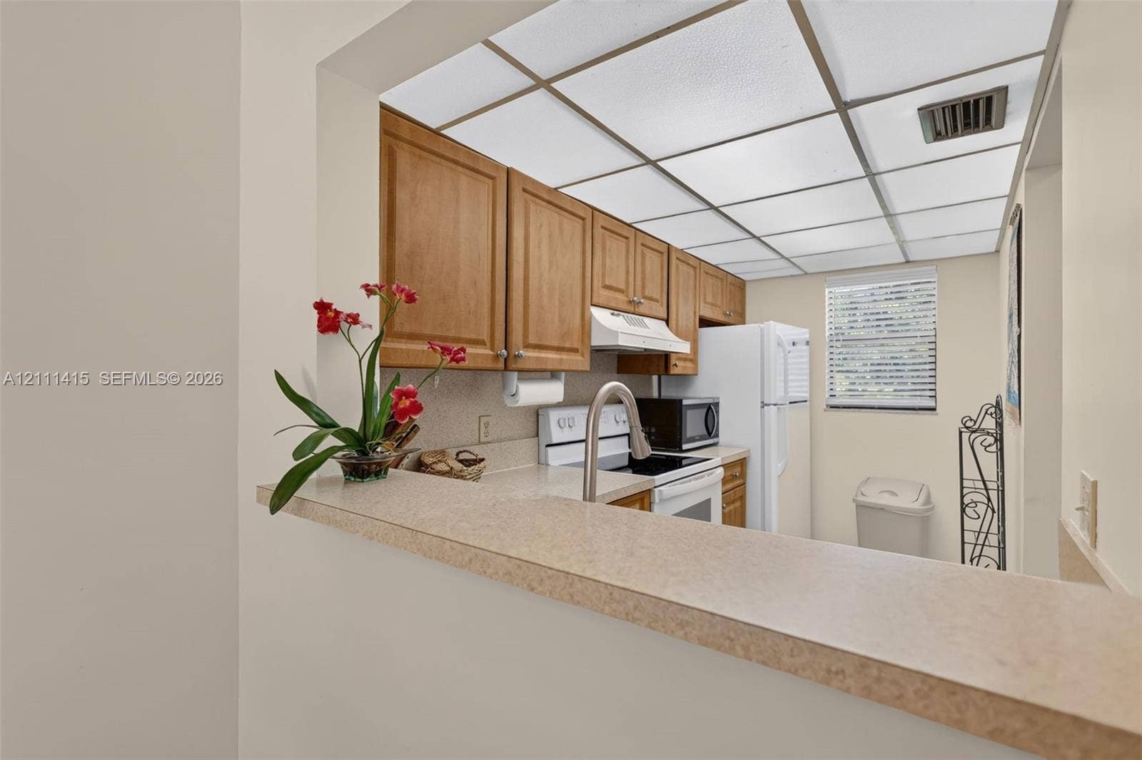 9423 S Ocean Drive, #80, Jensen Beach, FL 34957 Kitchen featuring wood cabinetry, solid-surface countertops, a stainless steel gooseneck faucet, and white appliances